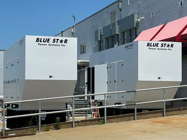 Two Blue Star Power Systems industrial generators outside a manufacturing facility 