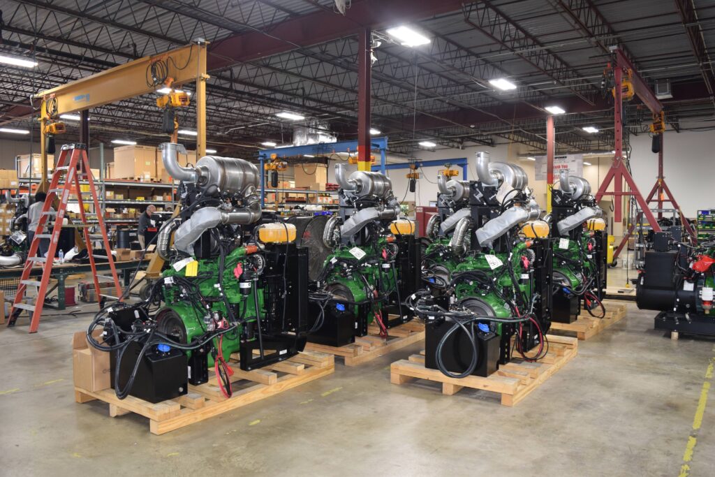 A row of industrial engines sitting on wooden pallets in a warehouse.