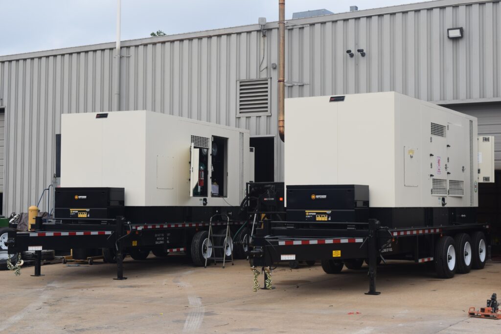 Two towable industrial generators sitting near a warehouse's loading zone.